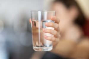Blog 47 A person holding a glass of clear drinking water
